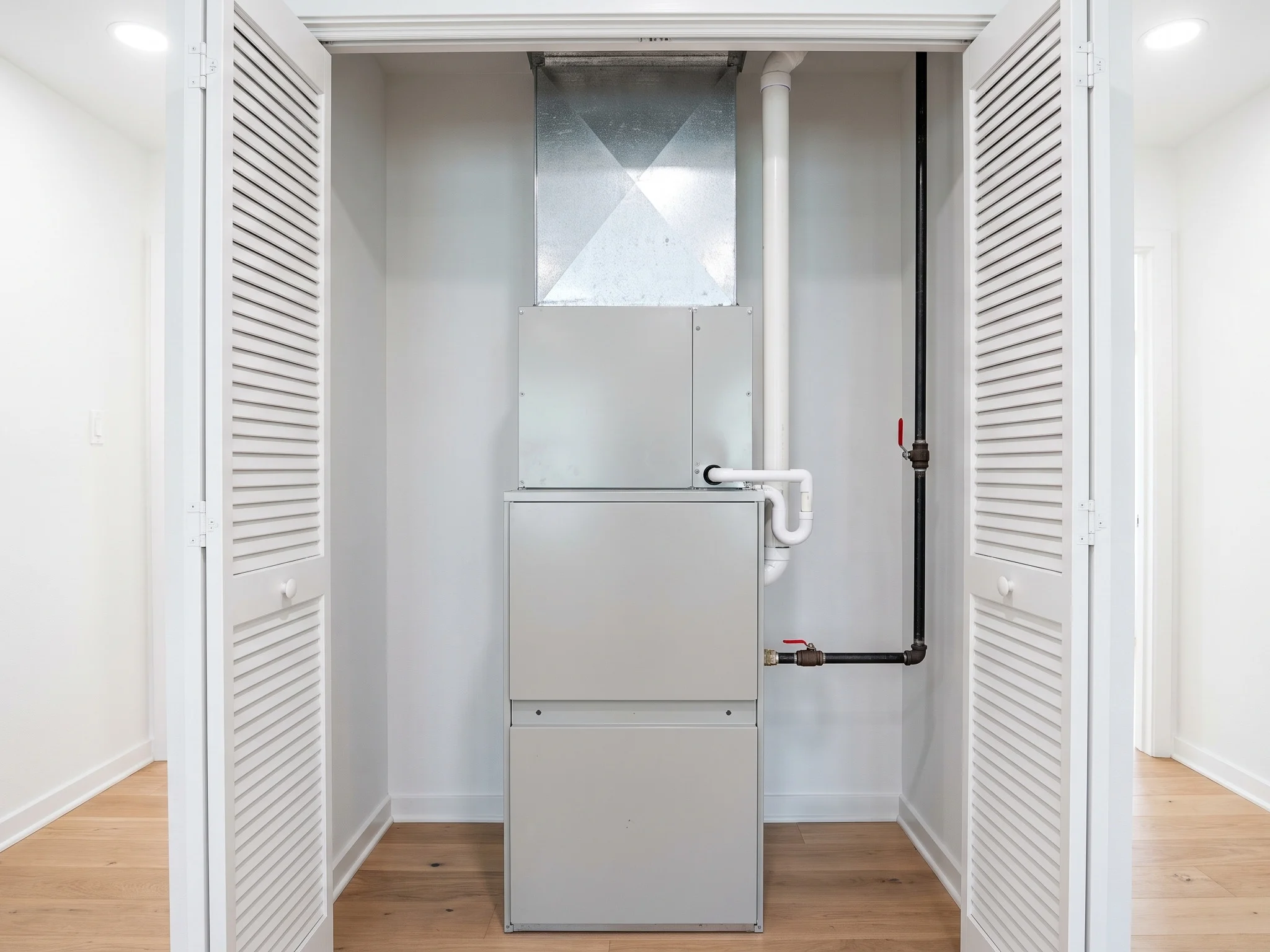 A new gas furnace and coil in a hallway utility closet